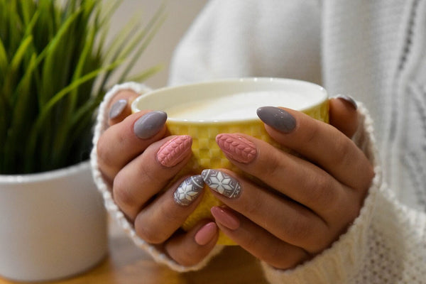 Hands Cupping Mug With Pink, White, and Grey Christmas Nail Art