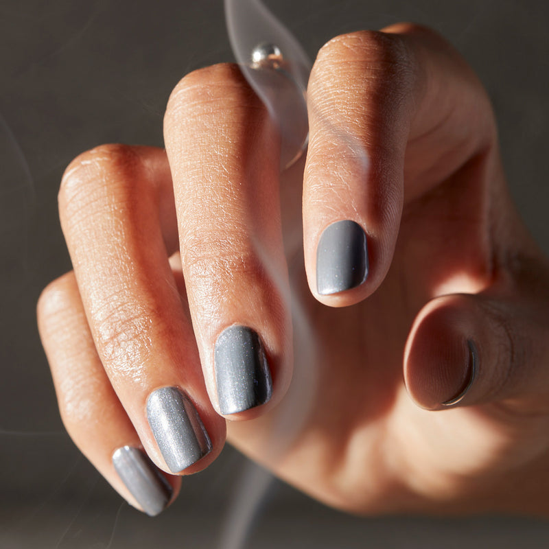 Hand with grey metallic nails and smoke